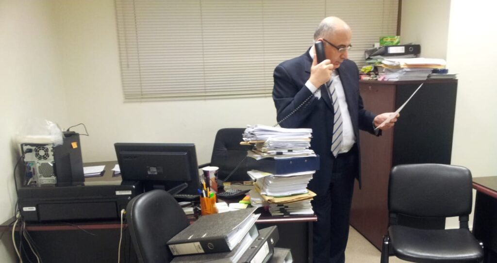 Joseph Deeb reviewing a document while taking a call in the Ministry of Energy and Water offices